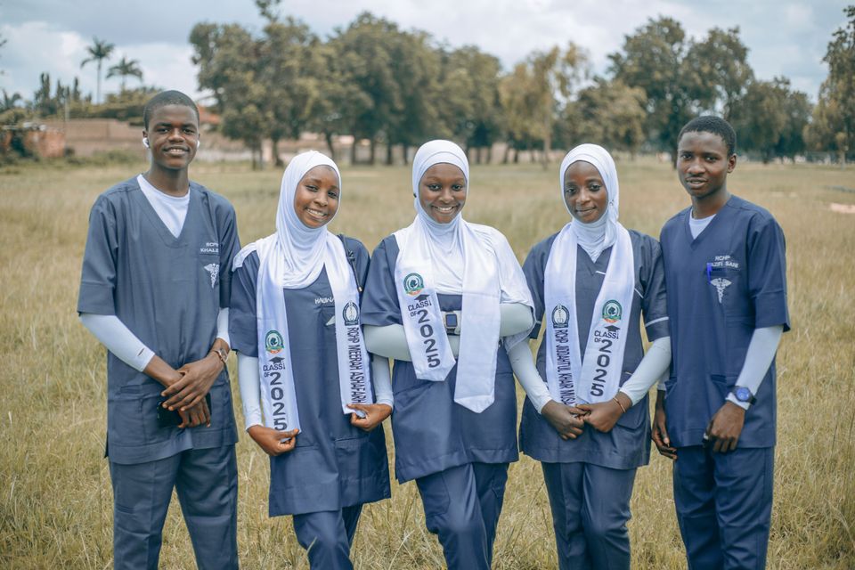 Five smiling nursing students standing together outdoors
