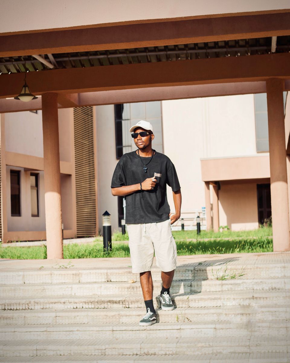 A young man walking confidently across a sunny campus