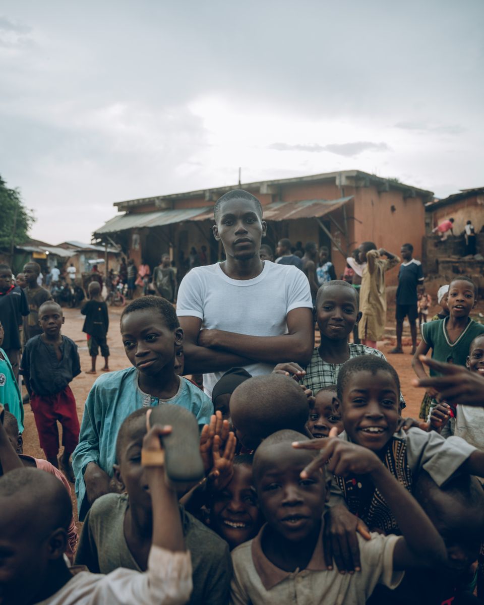A young man surrounded by cheerful children in a rural community