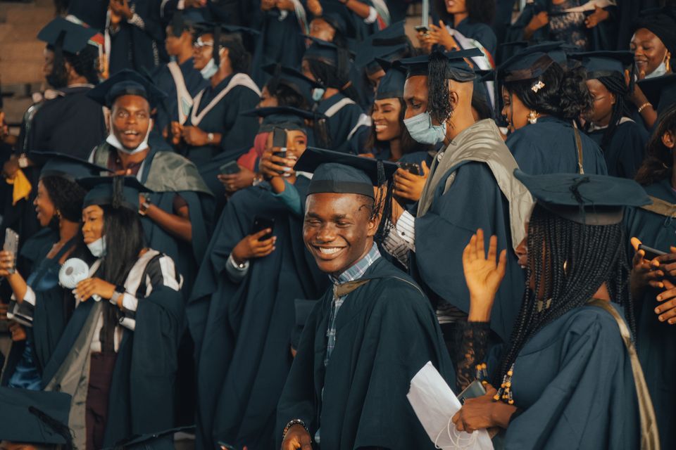 Joyful Nigerian graduates celebrating in their gowns at a university convocation